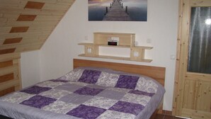 A bedroom with a bed, a wooden shelf with clocks, and a picture of a pier. - Appartement in Steinhude mit Grill by Interhome (Wunstorf)