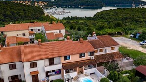 Un quartier résidentiel caractérisé par des toits recouverts de tuiles en terre cuite, une piscine et une vue sur un lac où naviguent des bateaux.