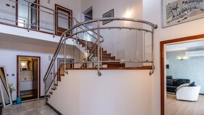 Un intérieur spacieux agrémenté d’un escalier en colimaçon, d’un coin salon avec un canapé et d’une œuvre d’art encadrée au mur.
