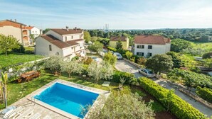 Ein Wohngebiet mit Schwimmbad, Häusern mit roten Ziegeldächern und einer Straße im Hintergrund.