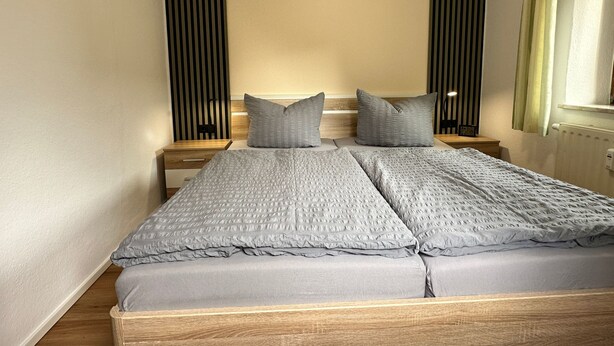 A double bed with grey bedding, wooden headboard, and two bedside tables with lamps. - Apartment Wuff by Interhome (Altendorf)