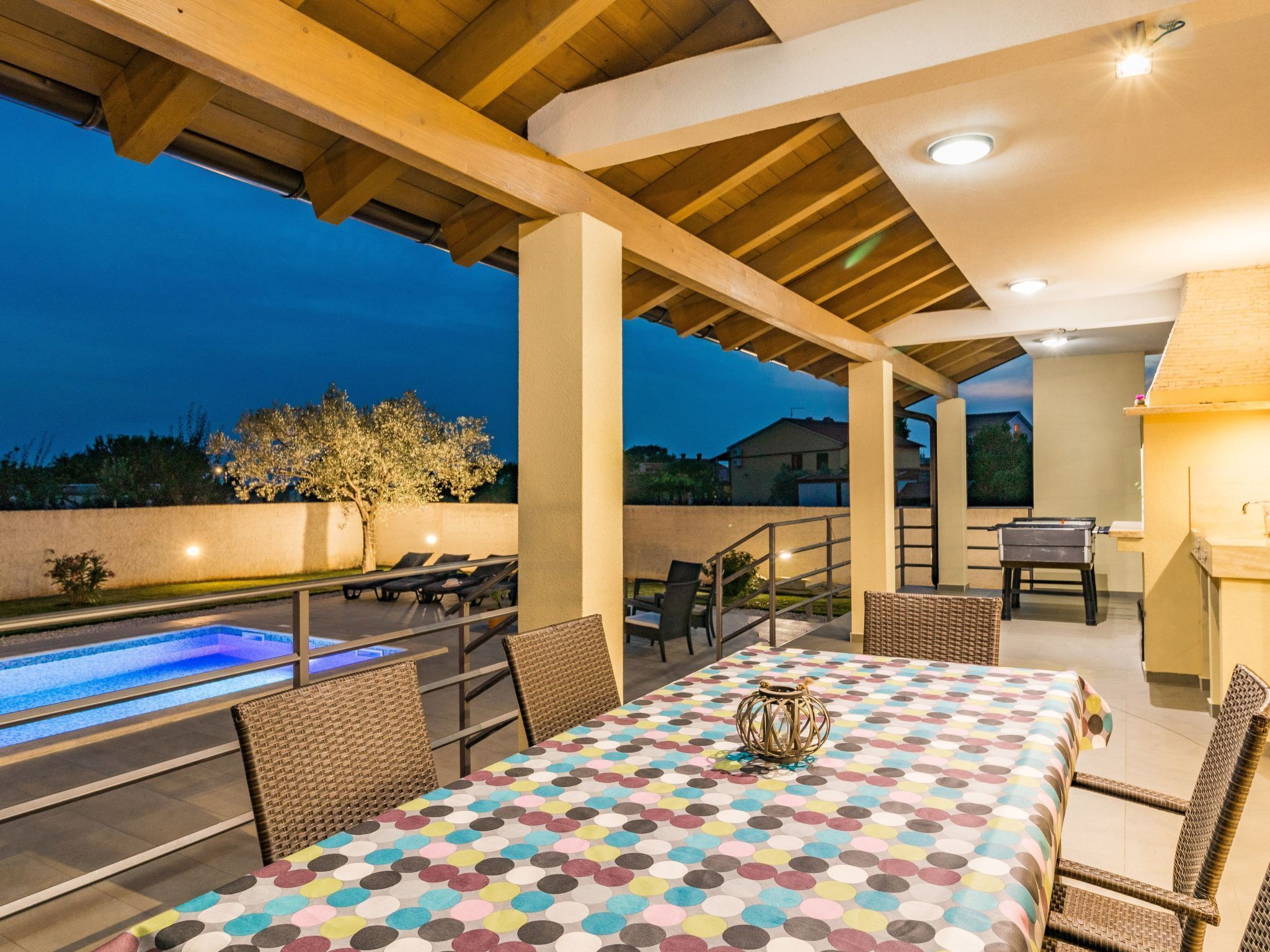 Une terrasse extérieure avec une piscine, une table à manger et des chaises.