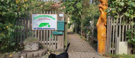 En kullerstensgång leder fram till en träport med en skylt där det står: ”Familienferienhof Sell’s Scheune”.