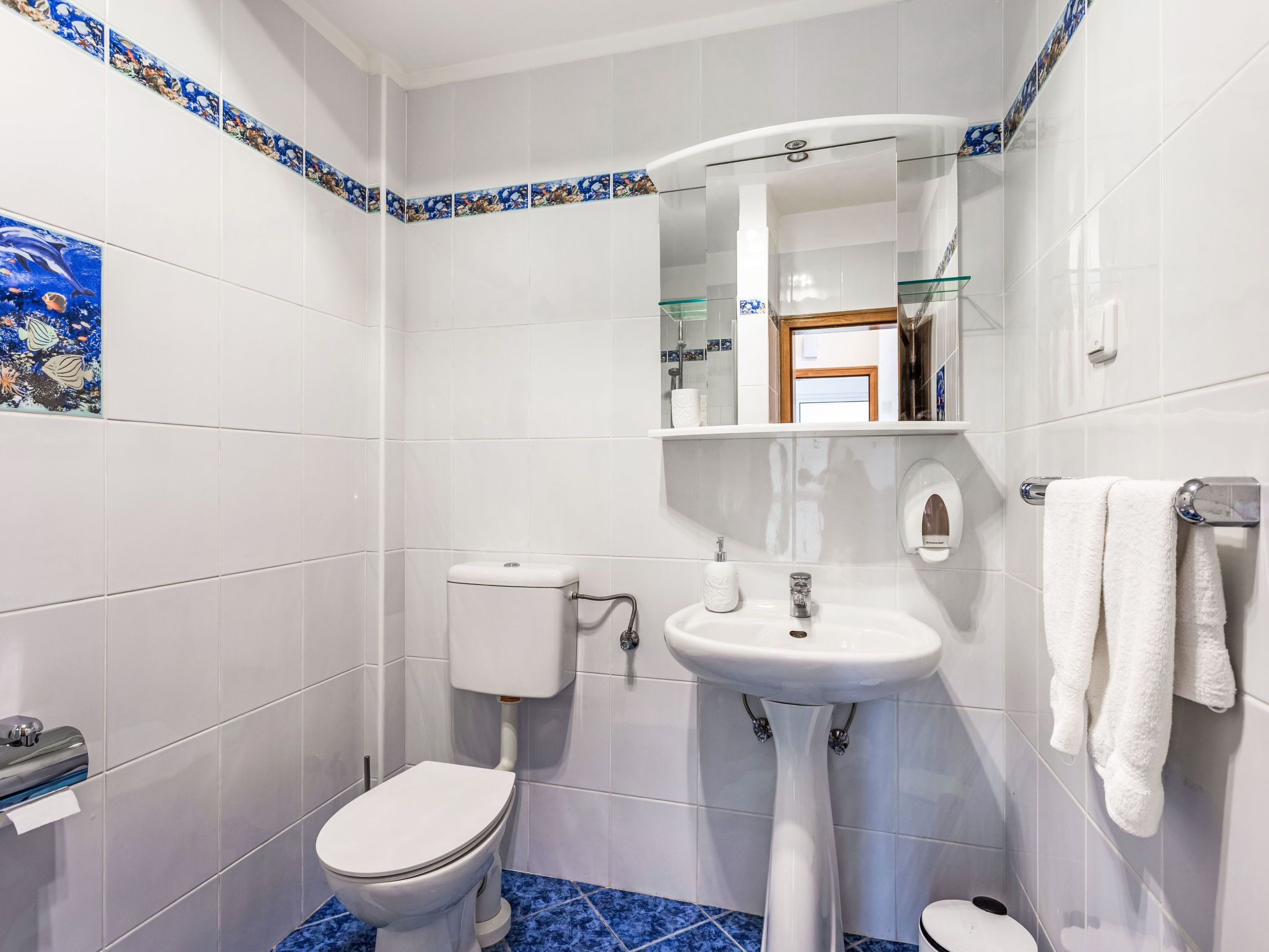 Une salle de bain avec des toilettes, un lavabo et un miroir.