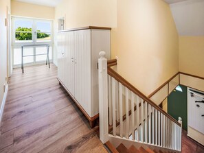 Ein Flur mit Holzboden, weißen Schränken und einer Treppe mit Holzwurf.