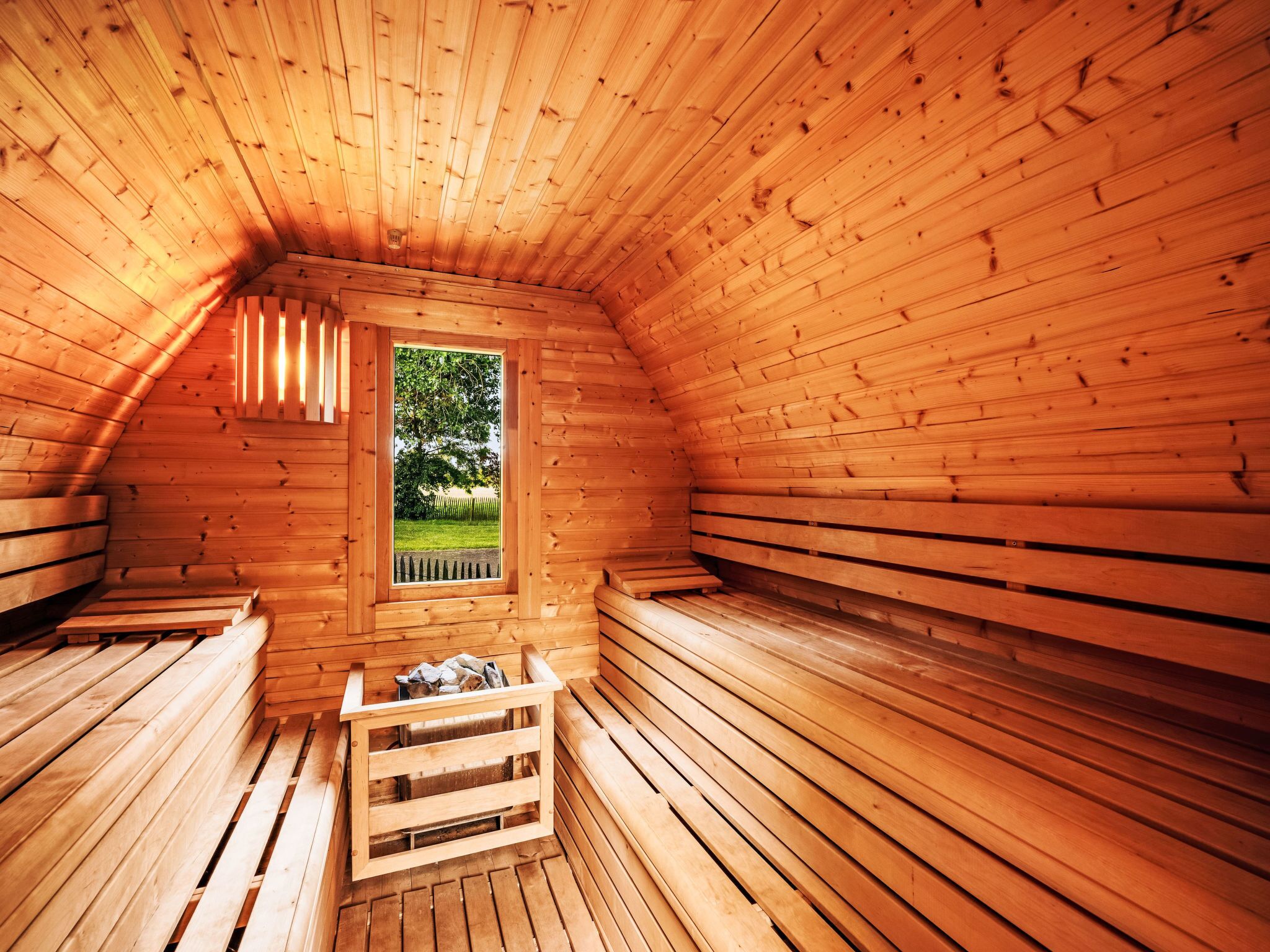 A wooden sauna room with benches and a window.