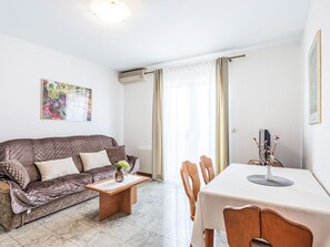 A living room with a sofa, a wooden coffee table, a dining table with chairs, a radiator, and an air conditioning unit. - Sonne 3 Rovinj by Interhome (Rovinj)