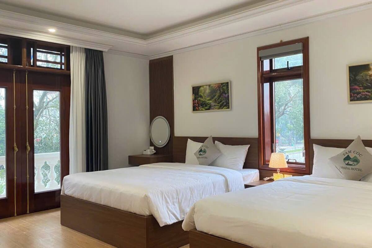 Une chambre d’hôtel avec deux lits, une grande fenêtre et des œuvres d’art aux murs.