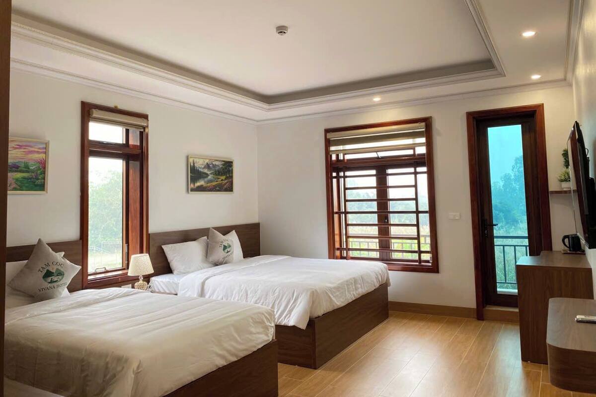 Une chambre d’hôtel avec deux lits, un bureau et un balcon.