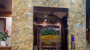 Een lift met een marmeren wand en een eethoek met een geel tafelkleed.