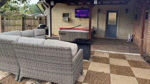 Ein überdachter Patio-Bereich mit Rattan-Sofa und Grill.