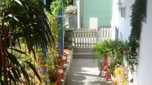 Un espace extérieur abrité, agrémenté de plantes en pot et délimité par une clôture blanche.