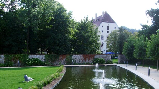 Une cour paisible avec une fontaine, une pelouse bien entretenue et un mur de pierre.