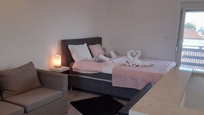 A bedroom with a bed, a nightstand, a sofa, and a view of the outside. - Apartment Smokvica by Interhome (Umag/Savudrija)