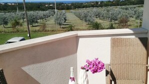 A balcony with wicker furniture, a table, and a bottle of champagne. - Apartment Smokvica by Interhome (Umag/Savudrija)