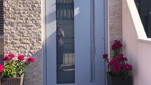 A modern apartment entrance with a stone facade, a white door, and a welcome mat. - Apartment Smokvica by Interhome (Umag/Savudrija)