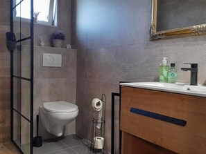 Ein modernes Badezimmer mit Toilette, Waschbecken und Duschbereich.
