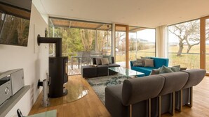 Un salon moderne avec une cheminée, un ensemble de canapés, une table basse et une vue sur l’extérieur.
