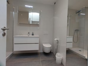 A modern bathroom with a white vanity, toilet, and glass shower enclosure. - Cristal 68 Attika by Interhome (Leukerbad)