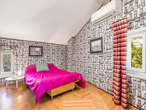 Een slaapkamer met een bed, een klein tafeltje en een raam met gordijnen.