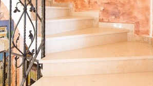 Una escalera con barandilla de hierro forjado que conduce a una plataforma. Encima de la escalera, hay tres obras de arte enmarcadas en la pared.