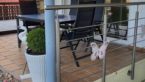 Un espace extérieur aménagé en terrasse, avec une table et des chaises, une plante en pot et une décoration en forme de papillon.