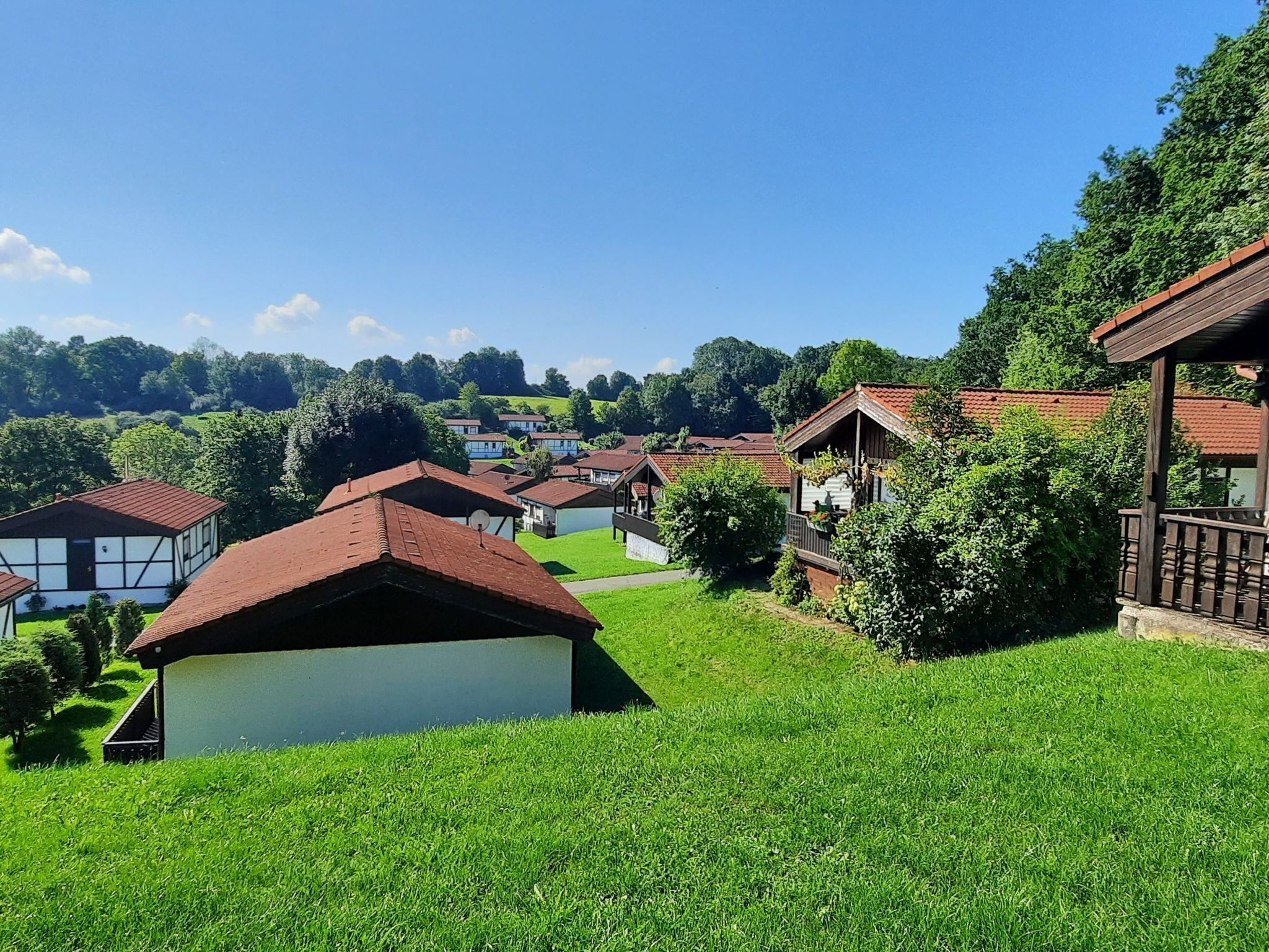 Ein ländliches Dorf mit traditionellen Häusern, blauem Himmel und üppigem Grün.