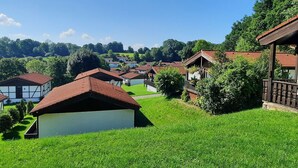 Un village rural avec des maisons traditionnelles, un ciel dégagé et une végétation luxuriante.