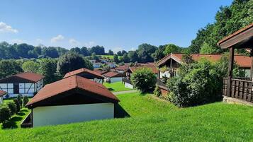 Ein ländliches Dorf mit traditionellen Häusern, blauem Himmel und üppigem Grün.