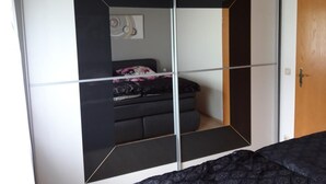 Une chambre à coucher avec un lit, une armoire avec un miroir et une porte.