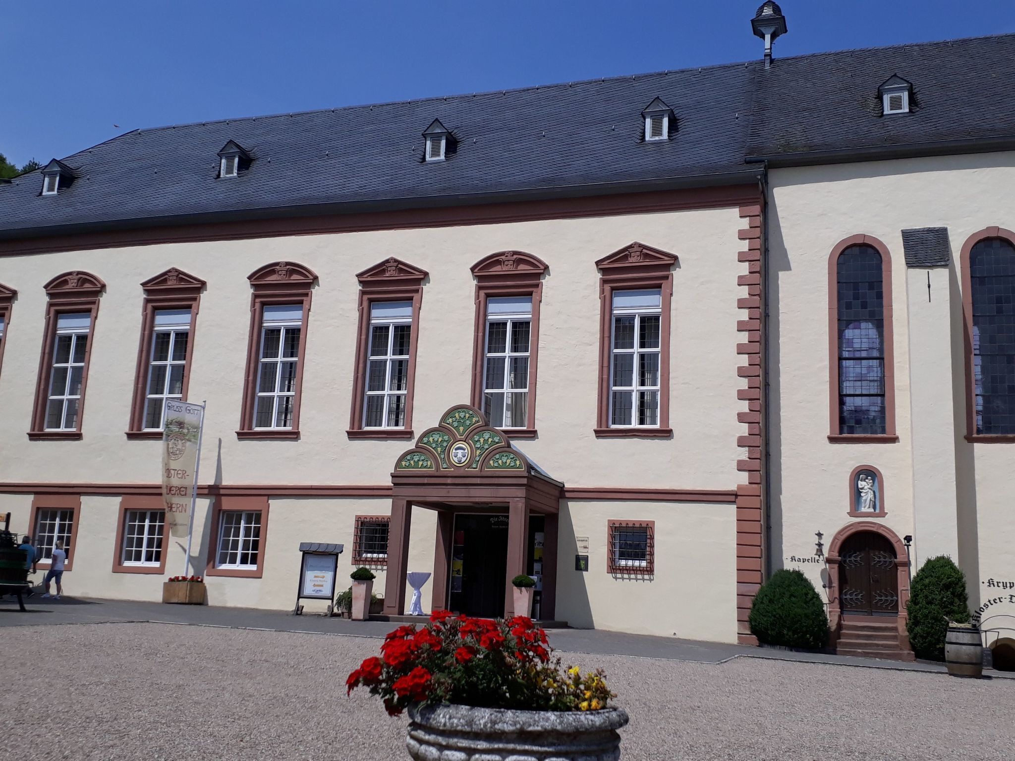 Ein historisches Gebäude mit einer symmetrischen Fassade, zahlreichen Fenstern und einem zentralen Eingang mit einem dekorativen Bogen.