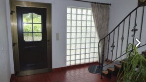 Una scala con ringhiera in metallo, una porta con pannello di vetro e una finestra con tenda.