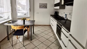 Et moderne køkken med spisebord, stole, komfur og vask.