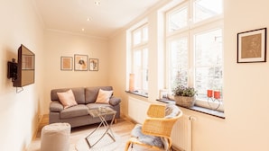 A modern living room with a grey sofa, a wicker chair, a glass coffee table, and a large window with a view of the outside. - FeWo "Mosel Hygge" by Interhome (Winningen)