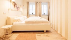 A modern bedroom with a large bed, a small table, and a window with curtains. - FeWo "Mosel Hygge" by Interhome (Winningen)