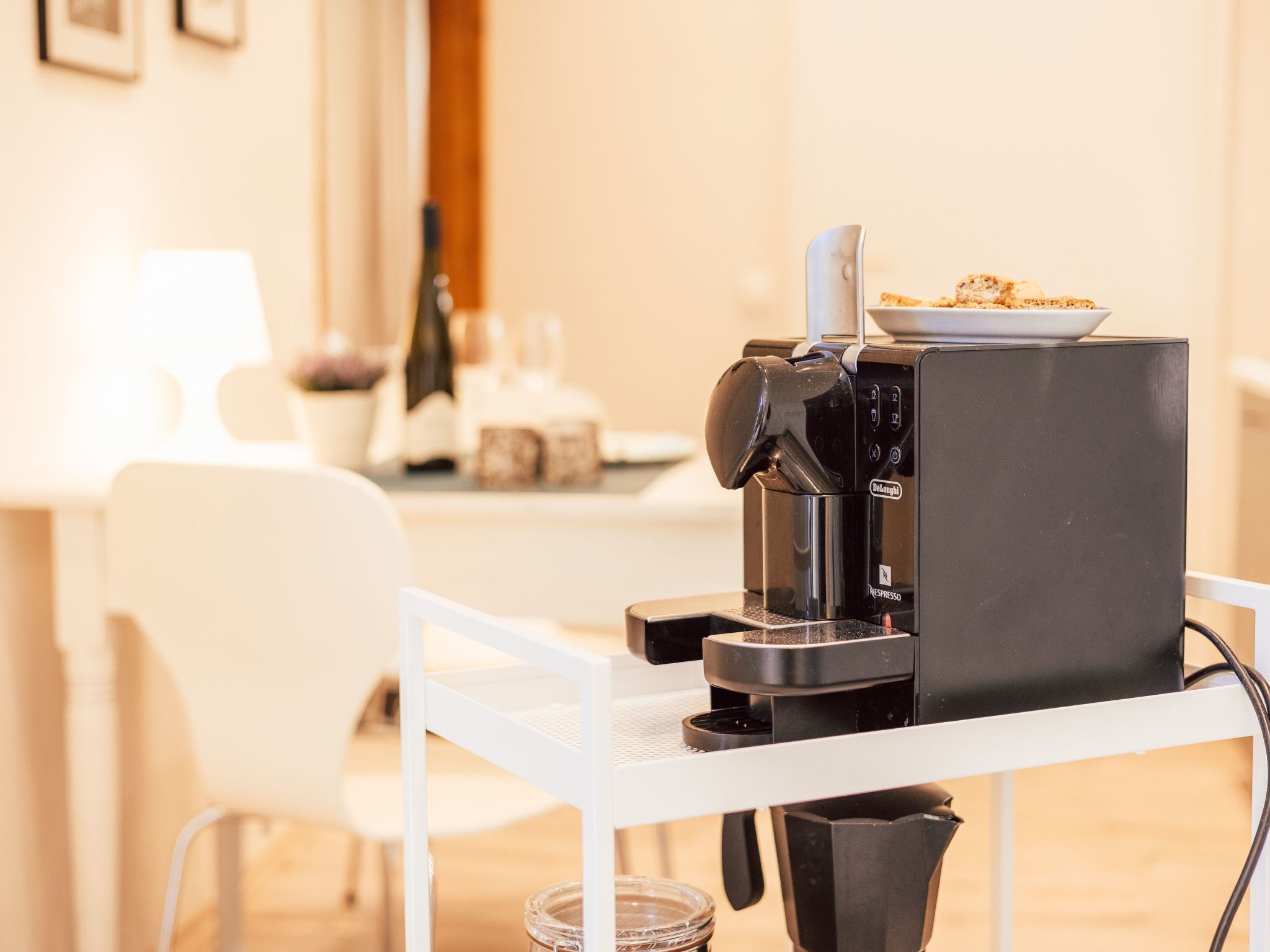 Eine Kaffeemaschine auf einem weißen Tisch, darauf ein Tablett mit Essen.