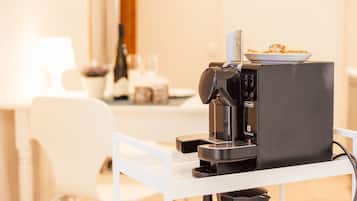 Eine Kaffeemaschine auf einem weißen Tisch, darauf ein Tablett mit Essen.