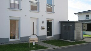 Een modern gebouw met twee verdiepingen, met een brievenbus waarop 'Ferien-Wohnung' staat, wat duidt op een vakantiewoning.