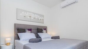 Un dormitorio moderno con una cama grande, cabecera y mesita de noche con lámpara.