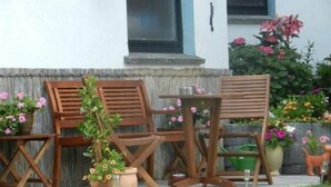 A patio with wooden furniture, a potted plant, and a small garden with flowers. - Preiser in Schieder-Schwalenberg by Interhome (Schieder-Schwalenberg)