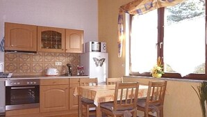 Una cocina con armarios de madera, una mesa de comedor con sillas y una ventana con cortinas.