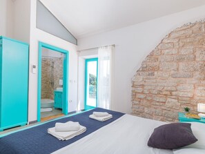 Ein Schlafzimmer mit Bett, ein Badezimmer mit Dusche und einer Steinsäule.