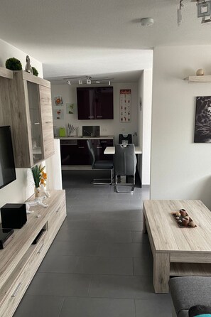 Un salon moderne avec un téléviseur à écran plat, une table basse en bois et un canapé.