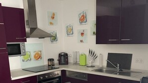 A modern kitchen with dark cabinets, a microwave, a stove, and a sink. There are framed pictures on the wall and a glass bowl on the table. - in ruhiger Lage in Seenähe by Interhome (Oberteuringen)