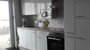 A modern kitchen with white cabinets, a stainless steel range hood, a microwave, and an oven. - Wohnung mit großer Gartenterrasse und Ausblick by Interhome (Argenbühl)