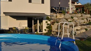 A modern house with a swimming pool, outdoor seating, and a stone wall. - Wohnung mit großer Gartenterrasse und Ausblick by Interhome (Argenbühl)