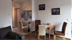 Ein modernes Wohnzimmer mit Sofa, Esstisch und Stühlen sowie einer Küchenzeile.
