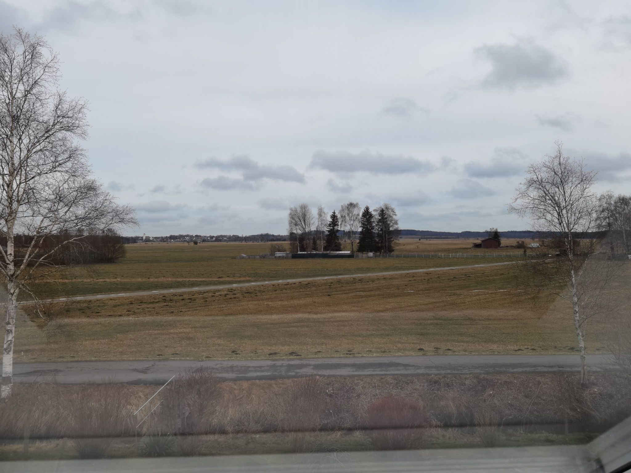 Un paysage rural caractérisé par de vastes champs, quelques arbres et des bâtiments situés au loin.