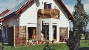 Ein zweistöckiges Haus mit geneigtem Dach, einem Balkon und einer Solaranlage auf dem Dach.