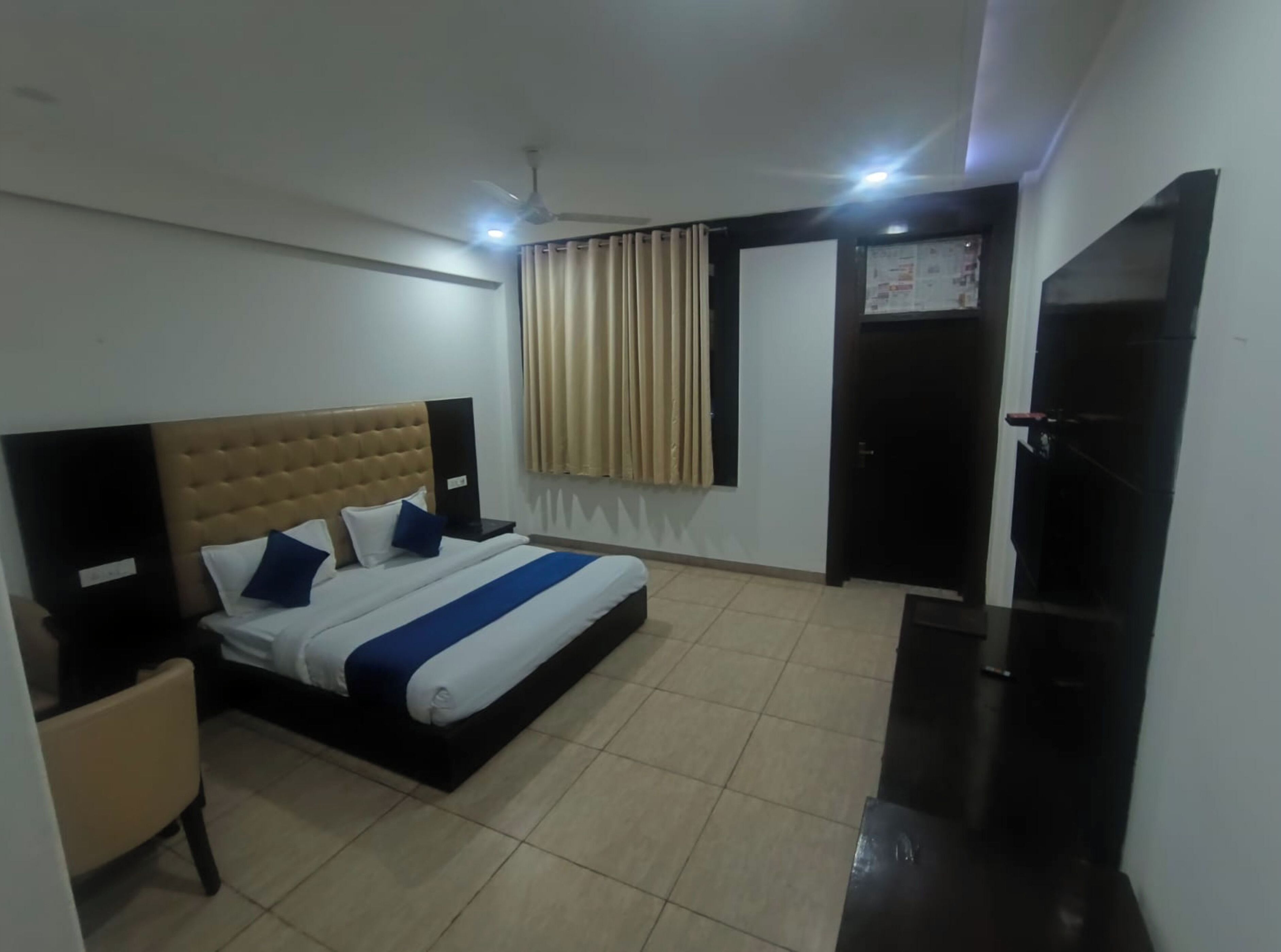 A hotel room with a bed, a desk, a chair, a TV, and a ceiling fan.